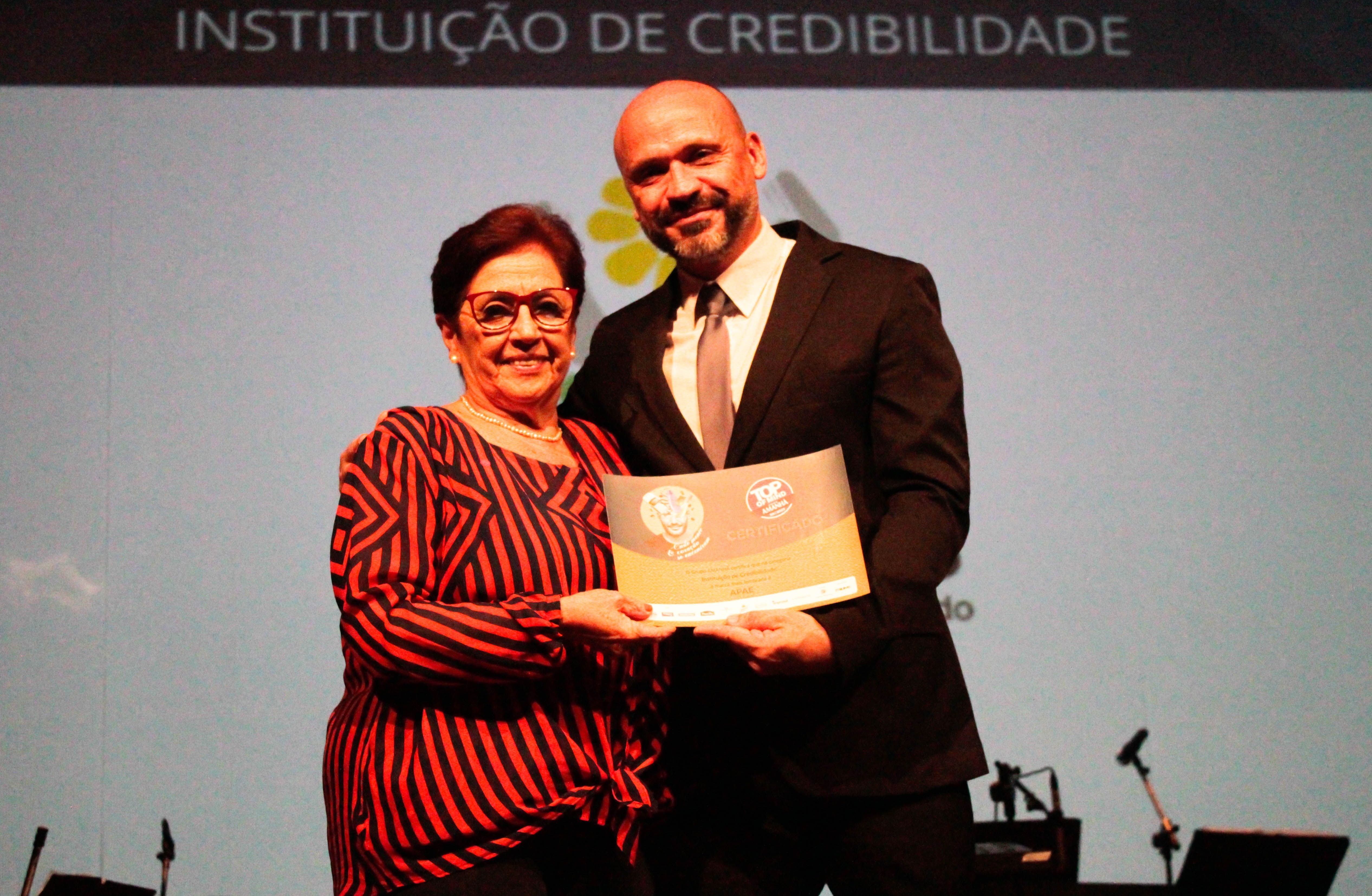 Aracy Ledo, presidente da FEAPAES-RS recebendo o certificado Top of Mind 2023.